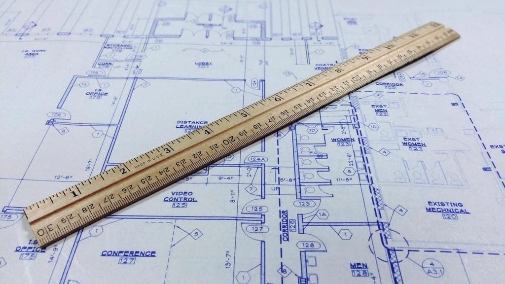 Wooden ruler lying across a blue printed floor plan