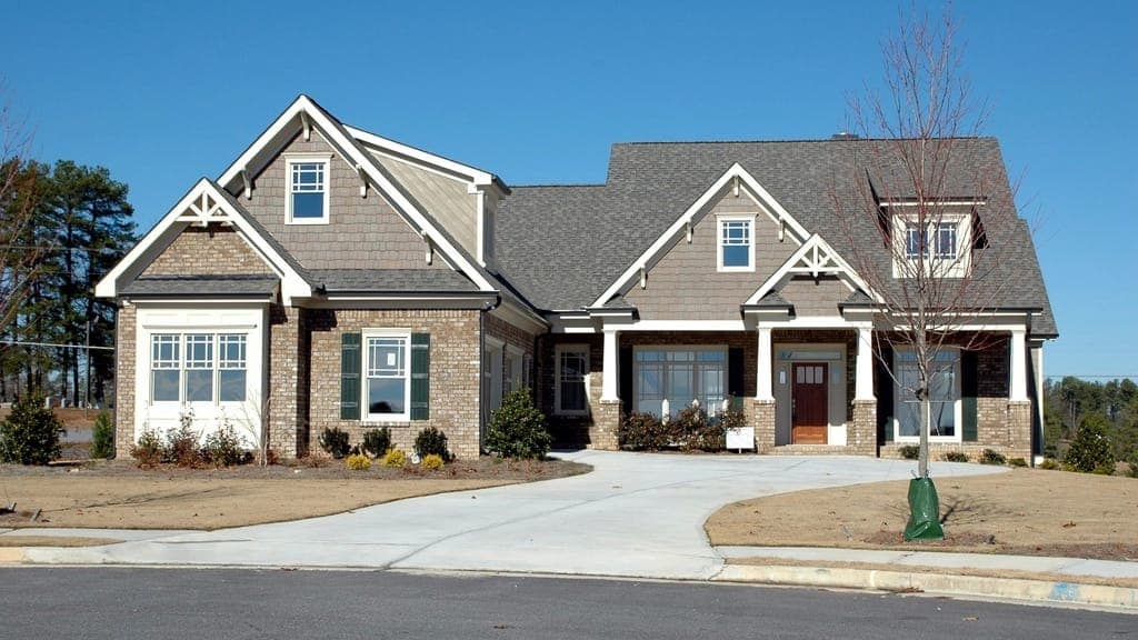 Brick and shingle-sided house with a wide curved concrete driveway on a cul-de-sac