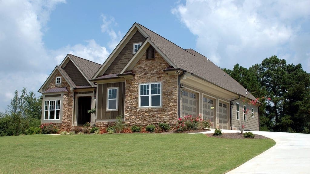 Stone and siding house with a three-car garage at the end of a curving driveway