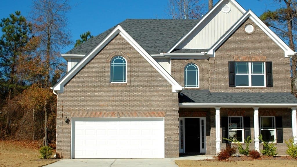 Two-story brick house with a white garage door and a small front porch