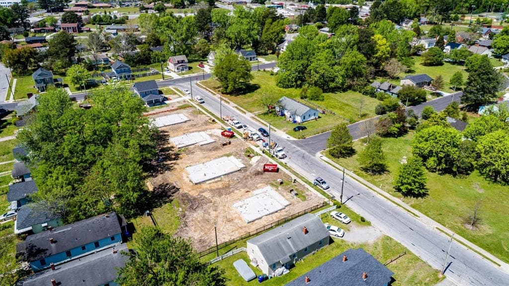Aerial view of a residential street with new house slabs poured on cleared lots between older homes